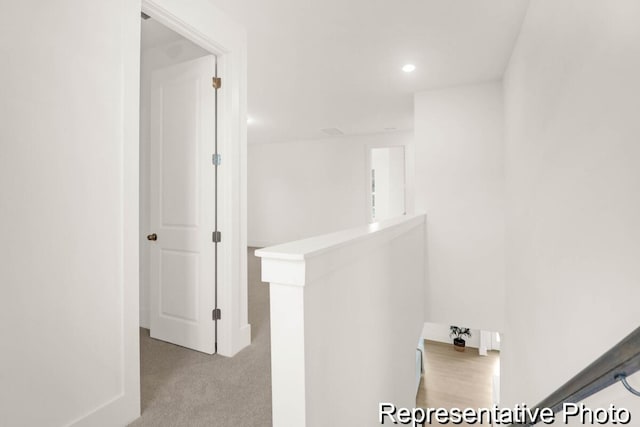 hall with recessed lighting, an upstairs landing, and carpet flooring