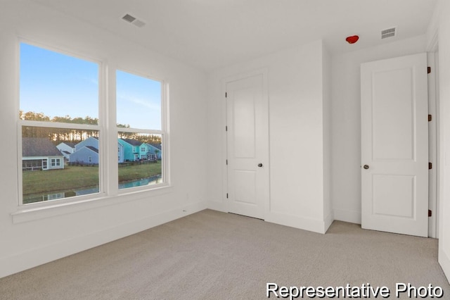 unfurnished bedroom featuring light carpet, visible vents, and baseboards