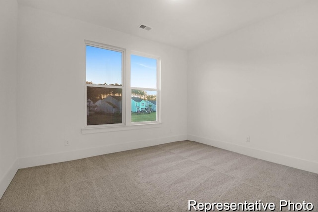 spare room featuring visible vents, light carpet, and baseboards