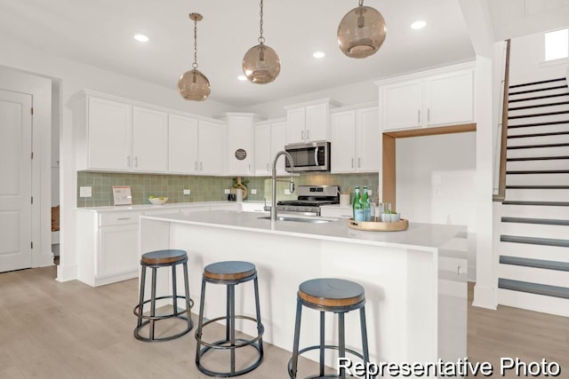 kitchen with light wood-style flooring, white cabinetry, stainless steel appliances, and light countertops