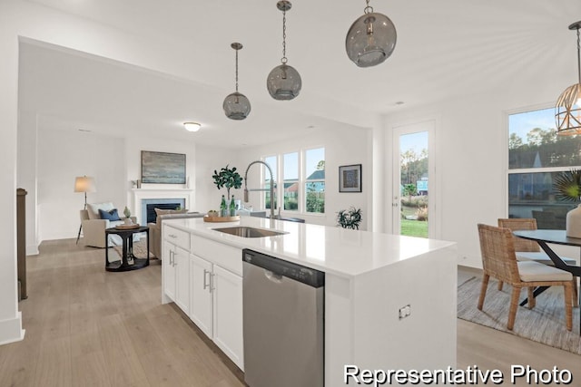 kitchen with a sink, light wood-style floors, stainless steel dishwasher, and a fireplace