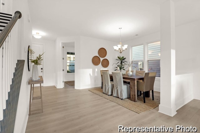 dining space with baseboards, light wood-style floors, a chandelier, and stairs