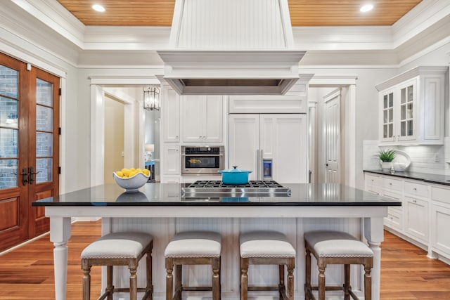 kitchen featuring appliances with stainless steel finishes, wood ceiling, white cabinetry, and a breakfast bar area