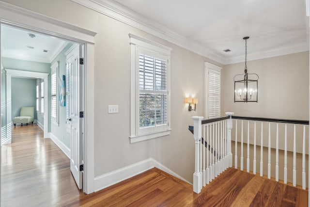 hallway with a notable chandelier, hardwood / wood-style flooring, and ornamental molding