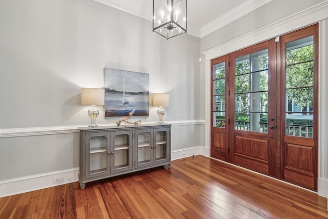 foyer entrance with an inviting chandelier, crown molding, and hardwood / wood-style flooring