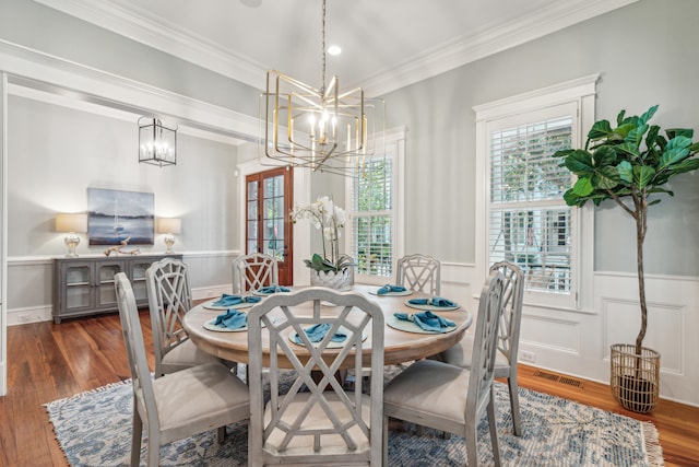 dining area featuring dark wood-type flooring, crown molding, and an inviting chandelier