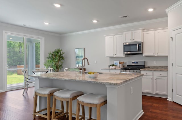 kitchen with white cabinets, stainless steel appliances, a sink, visible vents, and dark wood-type flooring