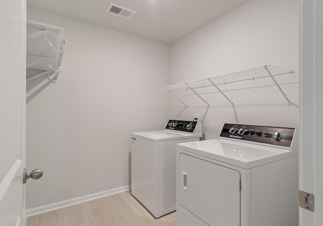 washroom with washing machine and dryer, baseboards, visible vents, and laundry area