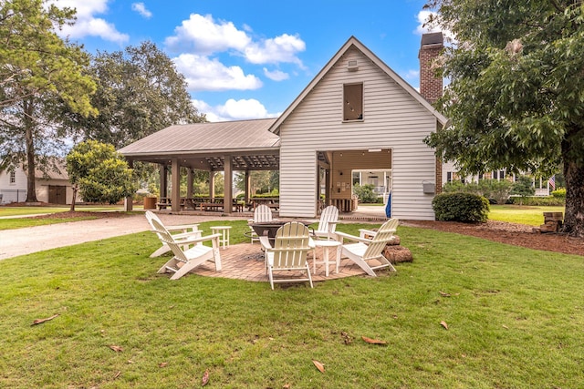 back of property with a fire pit, a chimney, and a yard