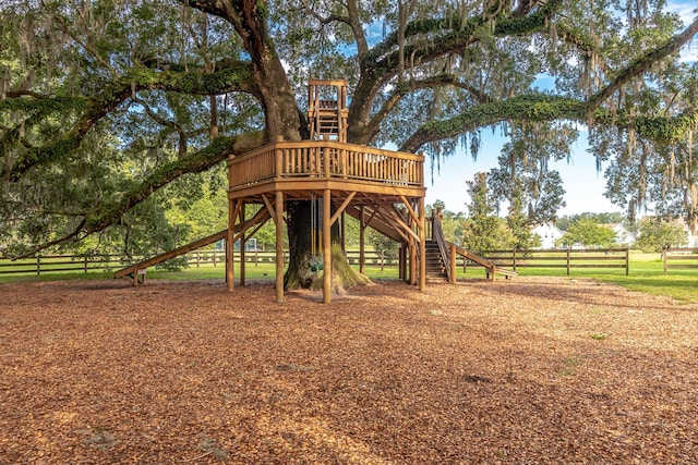 view of play area featuring a deck, stairway, and fence