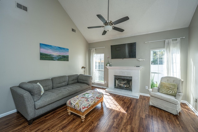 living room with a textured ceiling, ceiling fan, high vaulted ceiling, a fireplace, and dark hardwood / wood-style floors