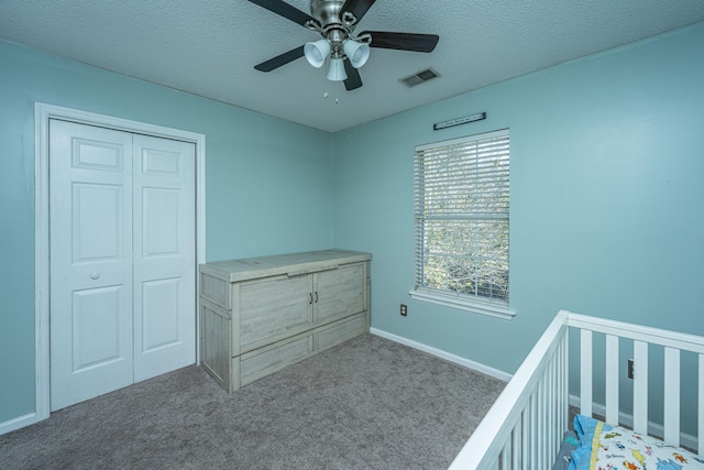 unfurnished bedroom featuring ceiling fan, light colored carpet, a textured ceiling, and a closet