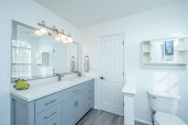 bathroom with hardwood / wood-style floors, vanity, toilet, and a textured ceiling