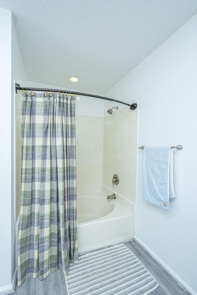 bathroom with a textured ceiling, hardwood / wood-style floors, and shower / tub combo