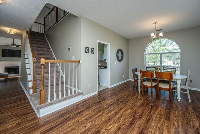 dining area featuring a textured ceiling, ceiling fan with notable chandelier, and dark wood-type flooring