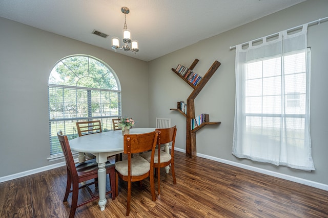 dining area with dark hardwood / wood-style floors and a notable chandelier