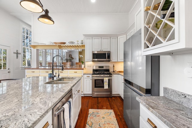 kitchen with sink, white cabinetry, dark hardwood / wood-style floors, stainless steel appliances, and light stone countertops