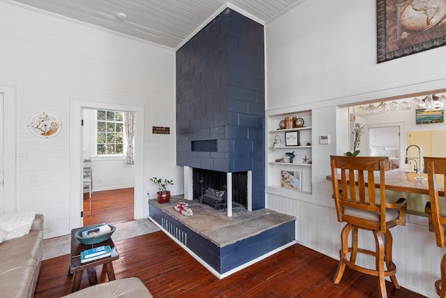 living room with a towering ceiling, a fireplace, dark hardwood / wood-style floors, and built in shelves