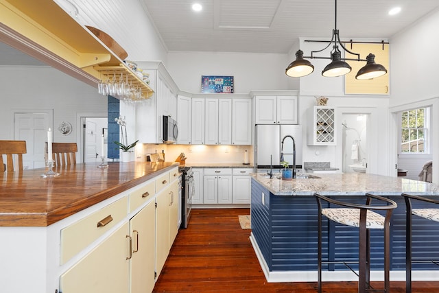 kitchen featuring sink, white cabinetry, stainless steel appliances, a kitchen breakfast bar, and light stone countertops