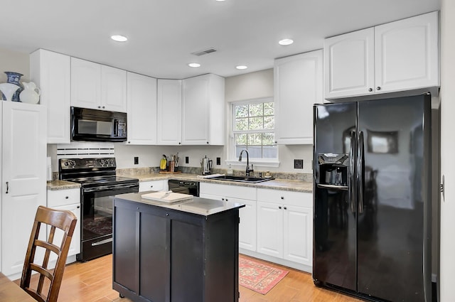 kitchen with black appliances, light wood-type flooring, a sink, and visible vents