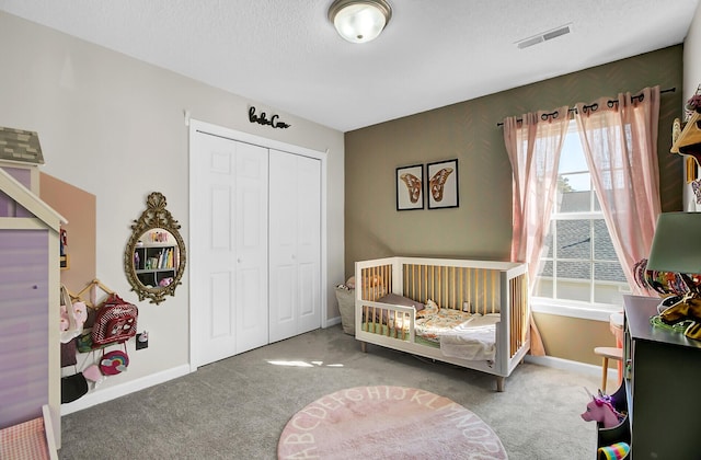 bedroom with a textured ceiling, a closet, carpet flooring, and visible vents