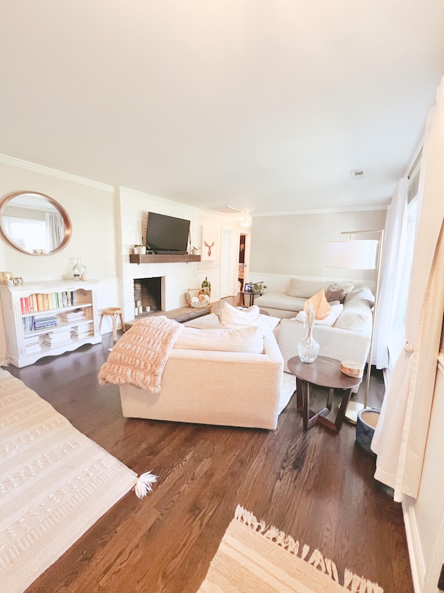 living room featuring a brick fireplace, dark wood-type flooring, and crown molding