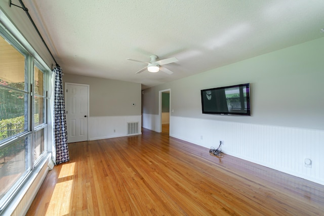 7 Plainfield Dr, Charleston, SC 29407 - unfurnished living room featuring light wood finished floors, a wainscoted wall, a textured ceiling, and a ceiling fan