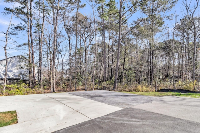 view of patio featuring aphalt driveway and a wooded view