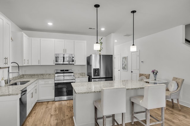 kitchen with a breakfast bar area, visible vents, a sink, stainless steel appliances, and a center island