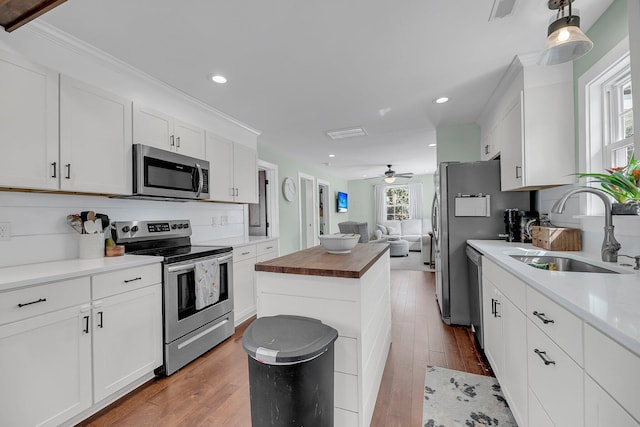 kitchen with white cabinets, wood counters, appliances with stainless steel finishes, wood finished floors, and a sink