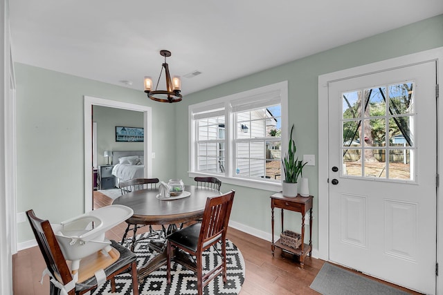 dining space featuring wood finished floors, visible vents, baseboards, and an inviting chandelier