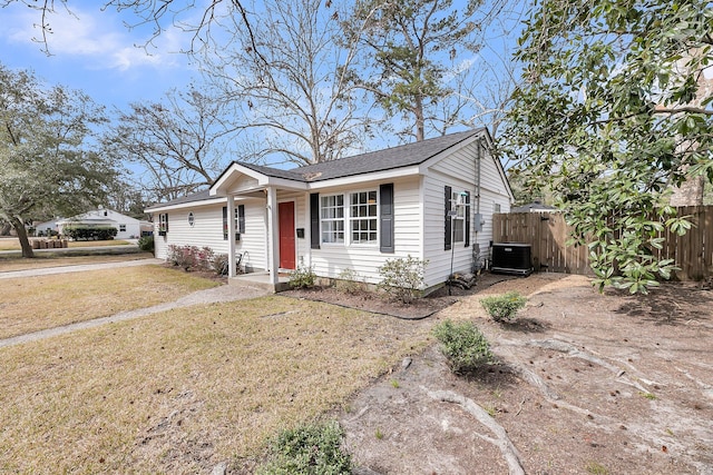 view of front of property with a shingled roof, fence, a front lawn, and central AC