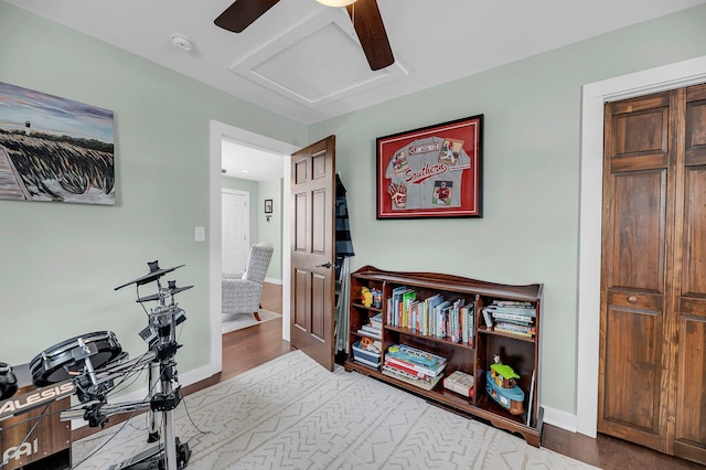 interior space with ceiling fan, wood finished floors, attic access, and baseboards