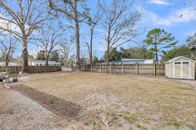 view of yard with a shed, a fenced backyard, and an outbuilding