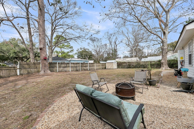 view of yard with an outbuilding, a storage unit, a fire pit, and a fenced backyard