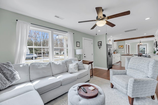 living room with light wood-style floors, visible vents, and a wealth of natural light