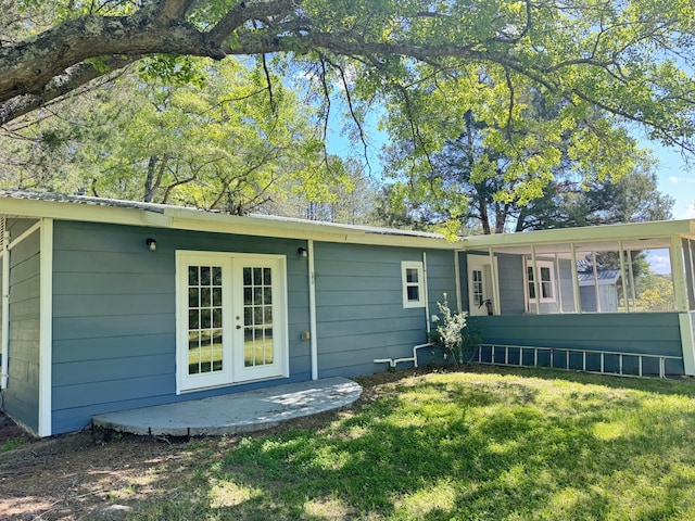 rear view of house with french doors and a lawn