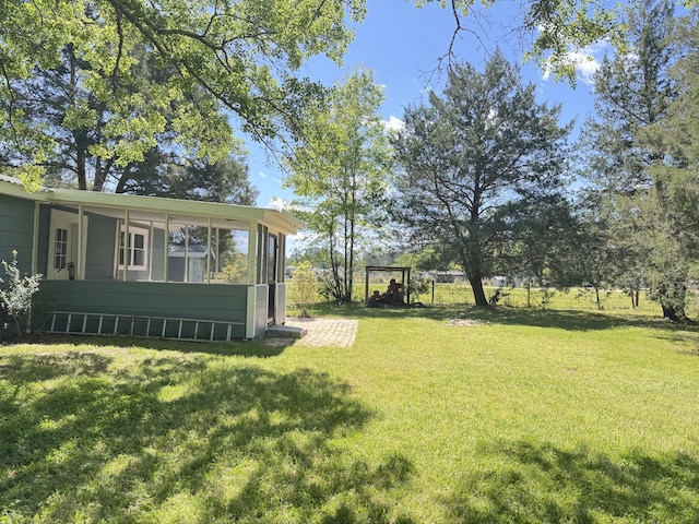 view of grassy yard with a sunroom