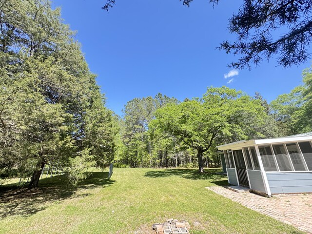 view of green lawn featuring a sunroom