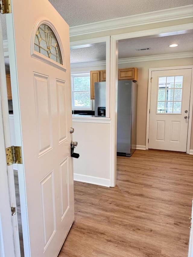 entryway with ornamental molding, light wood-style floors, baseboards, recessed lighting, and a textured ceiling
