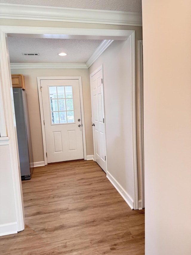 doorway featuring light wood finished floors, crown molding, baseboards, and recessed lighting