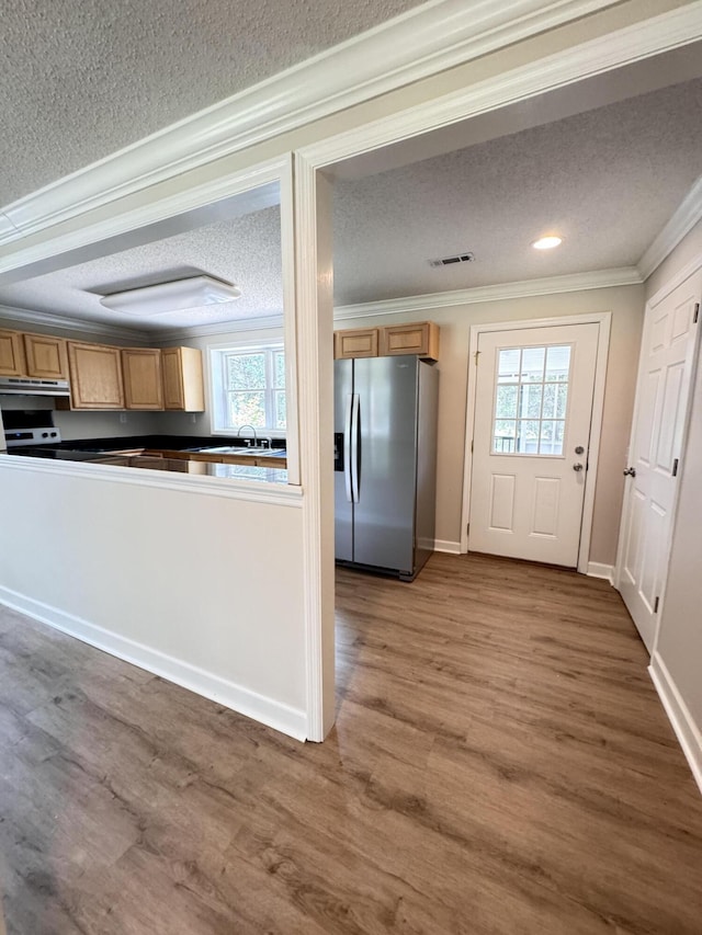 kitchen featuring stainless steel fridge with ice dispenser, a textured ceiling, crown molding, under cabinet range hood, and wood finished floors