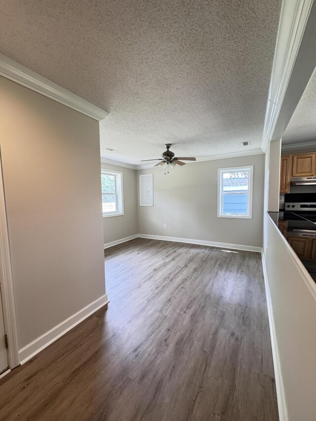 unfurnished living room with ornamental molding, dark wood-style flooring, a textured ceiling, a ceiling fan, and baseboards