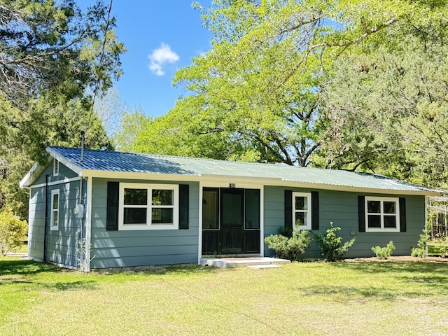 ranch-style home featuring a front lawn and metal roof