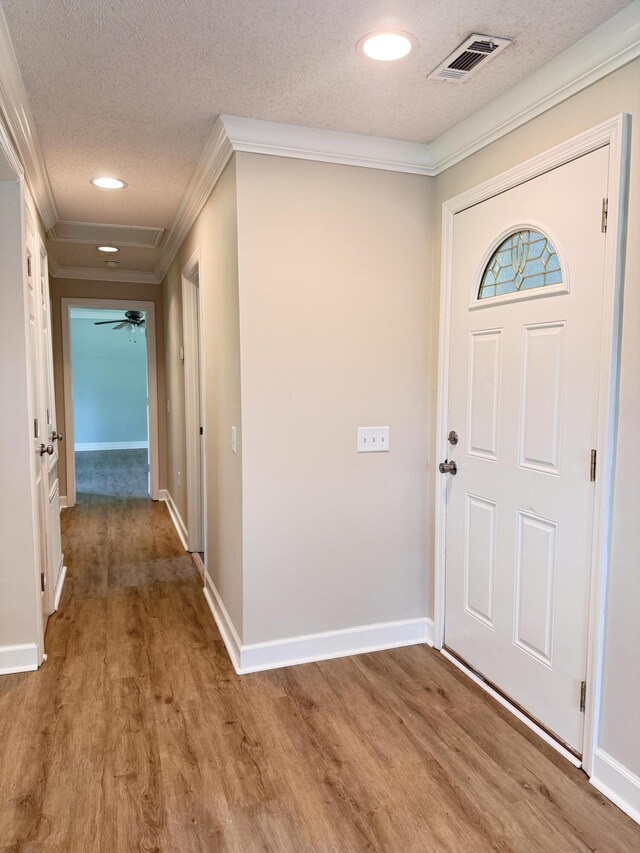 foyer featuring crown molding, a textured ceiling, wood finished floors, baseboards, and recessed lighting