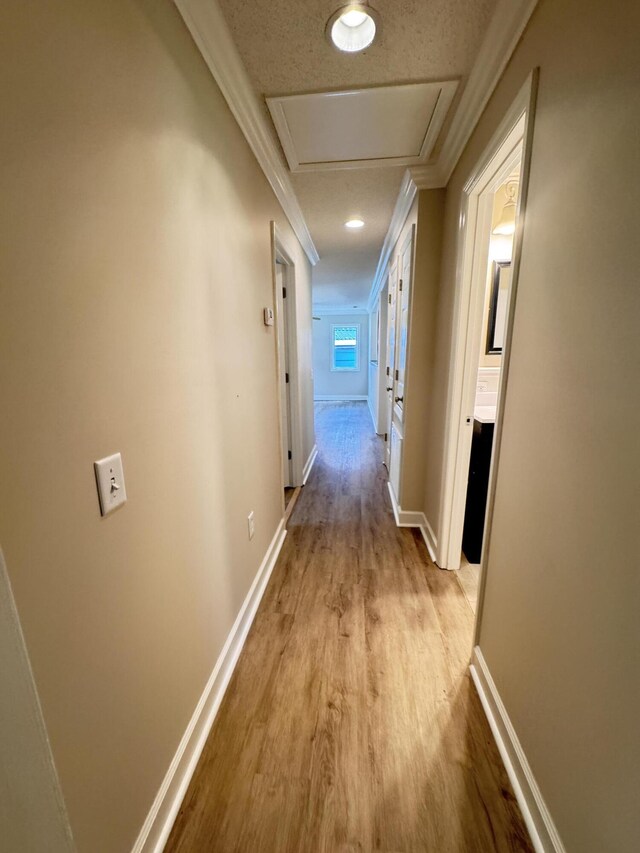 hallway featuring wood finished floors, baseboards, and crown molding