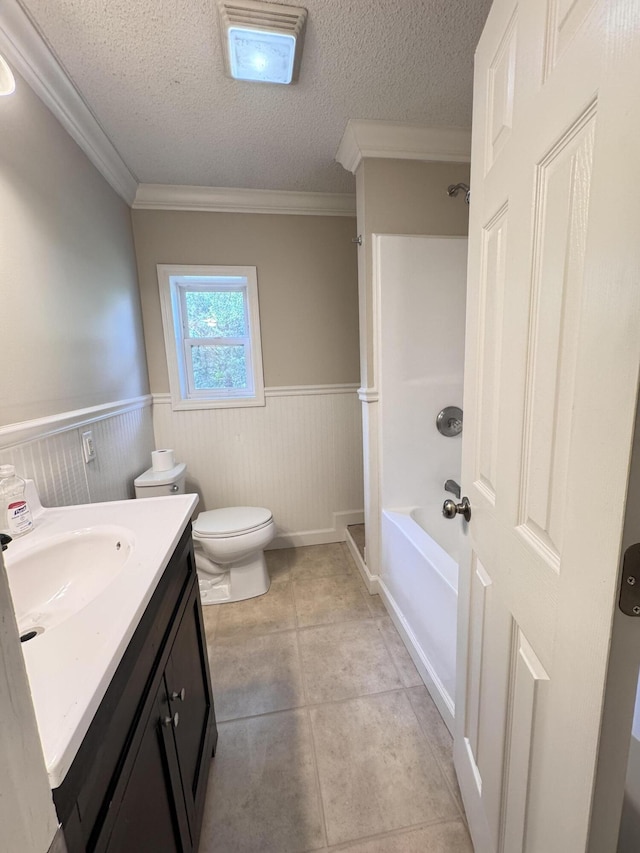 bathroom with wainscoting, toilet, vanity, crown molding, and a textured ceiling