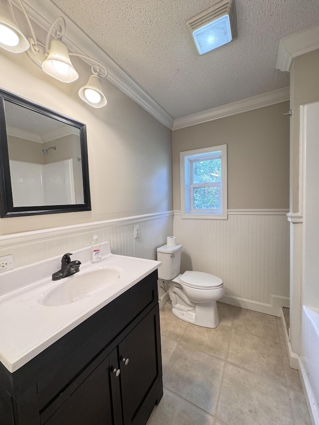 full bathroom with toilet, wainscoting, a shower, vanity, and crown molding