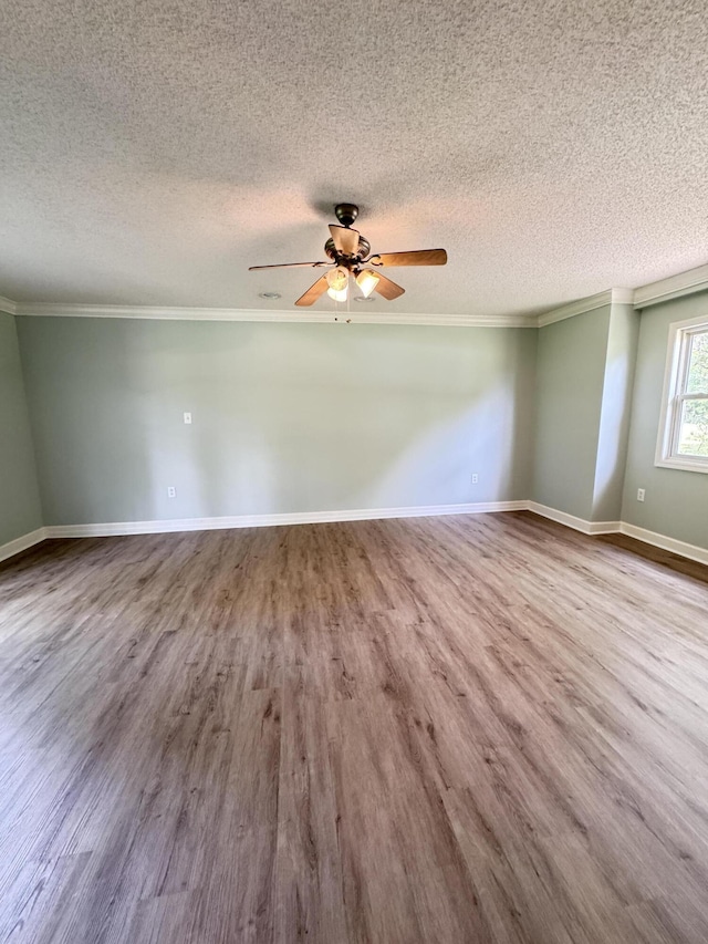 empty room with ornamental molding, wood finished floors, ceiling fan, a textured ceiling, and baseboards