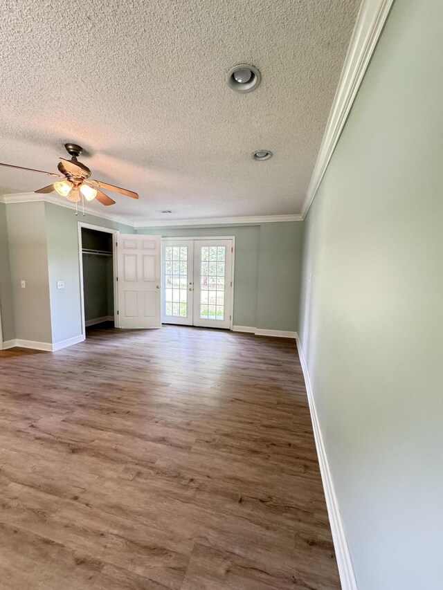 unfurnished bedroom with ornamental molding, a textured ceiling, baseboards, french doors, and wood finished floors